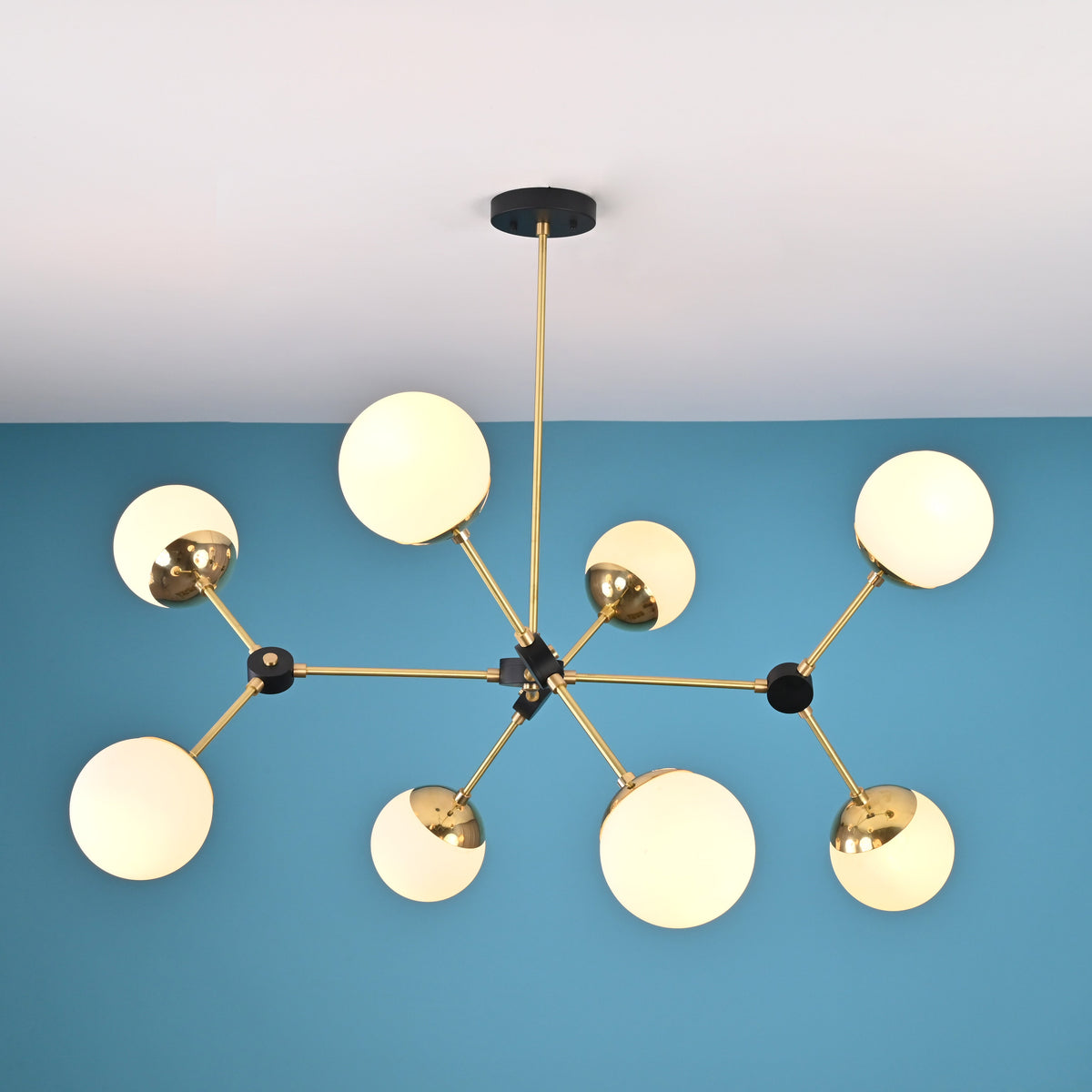 Top-down view of an 8-light brass sputnik chandelier displaying symmetrical arm layout and opal glass globe shades.