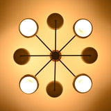Warm top-view photo of 8-light brass chandelier casting soft, diffused lighting through bowl-shaped shades.