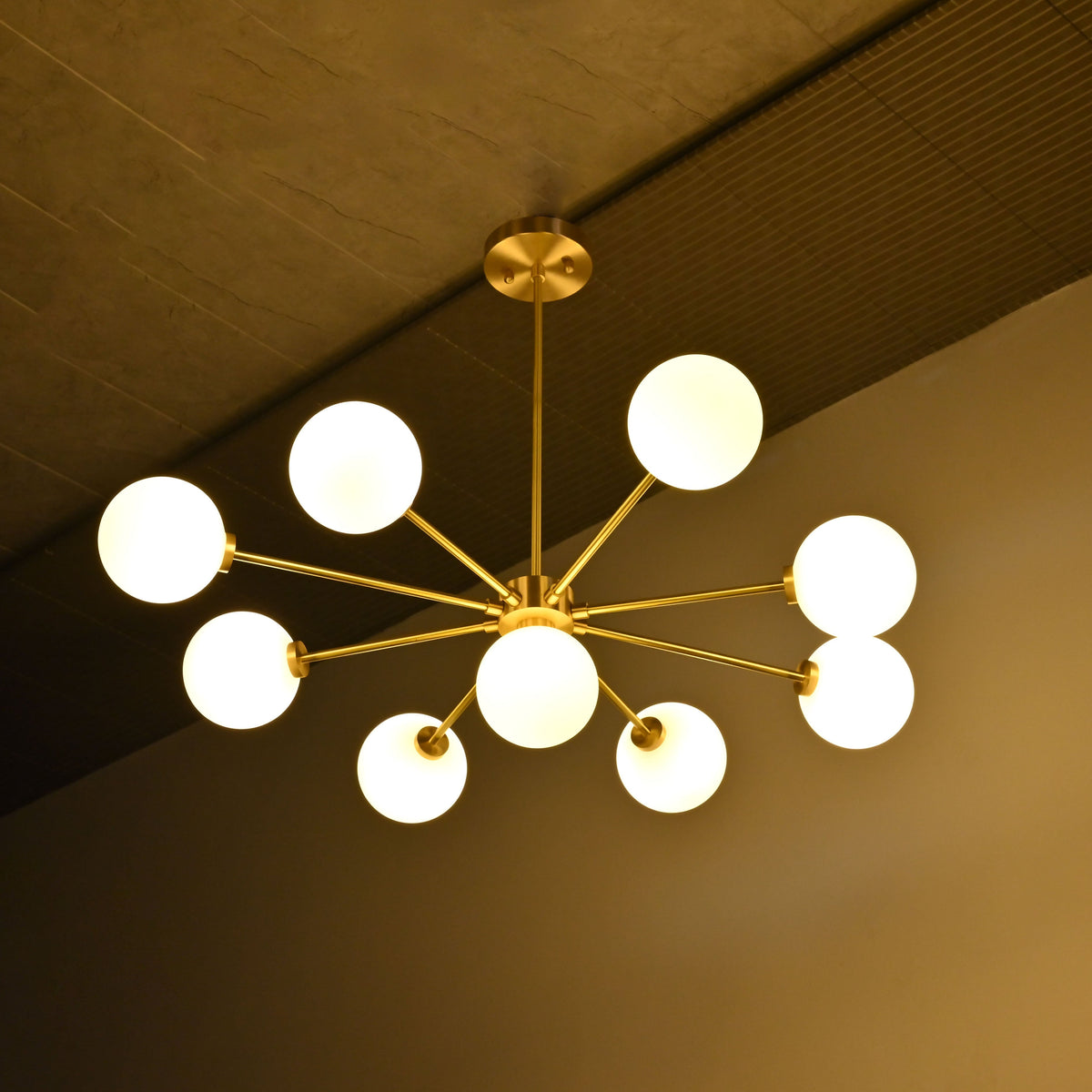 9-light brass chandelier shown illuminated with glowing glass globes and balanced Sputnik style arm layout
