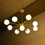 9-light brass chandelier shown illuminated with glowing glass globes and balanced Sputnik style arm layout