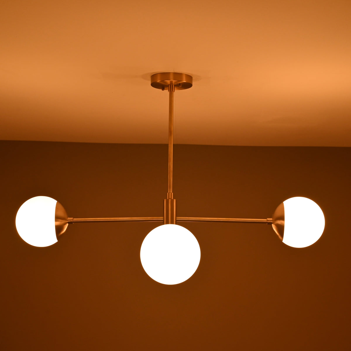 Astra 4 Globe Sputnik Chandelier installed on ceiling with warm glow and three visible round shades