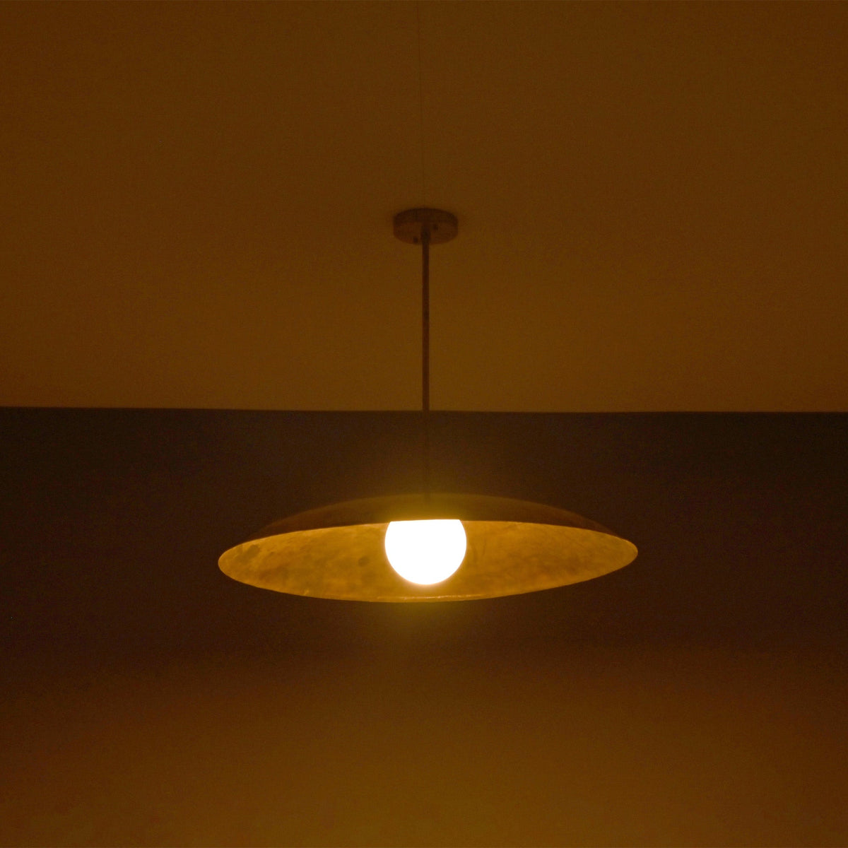 Wide evening view of Aurelia Globe Saucer Pendant Light highlighting the warm globe bulb and dome profile.