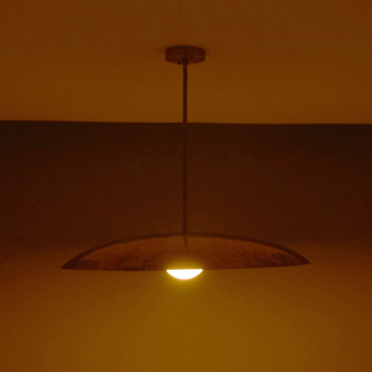 Side view of Aurelia Globe Saucer Pendant Light showing low saucer silhouette and downward warm glow.