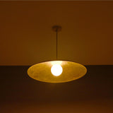 Aurelia Globe Saucer Pendant Light glowing in a dark setting with soft warm ambient lighting effect.