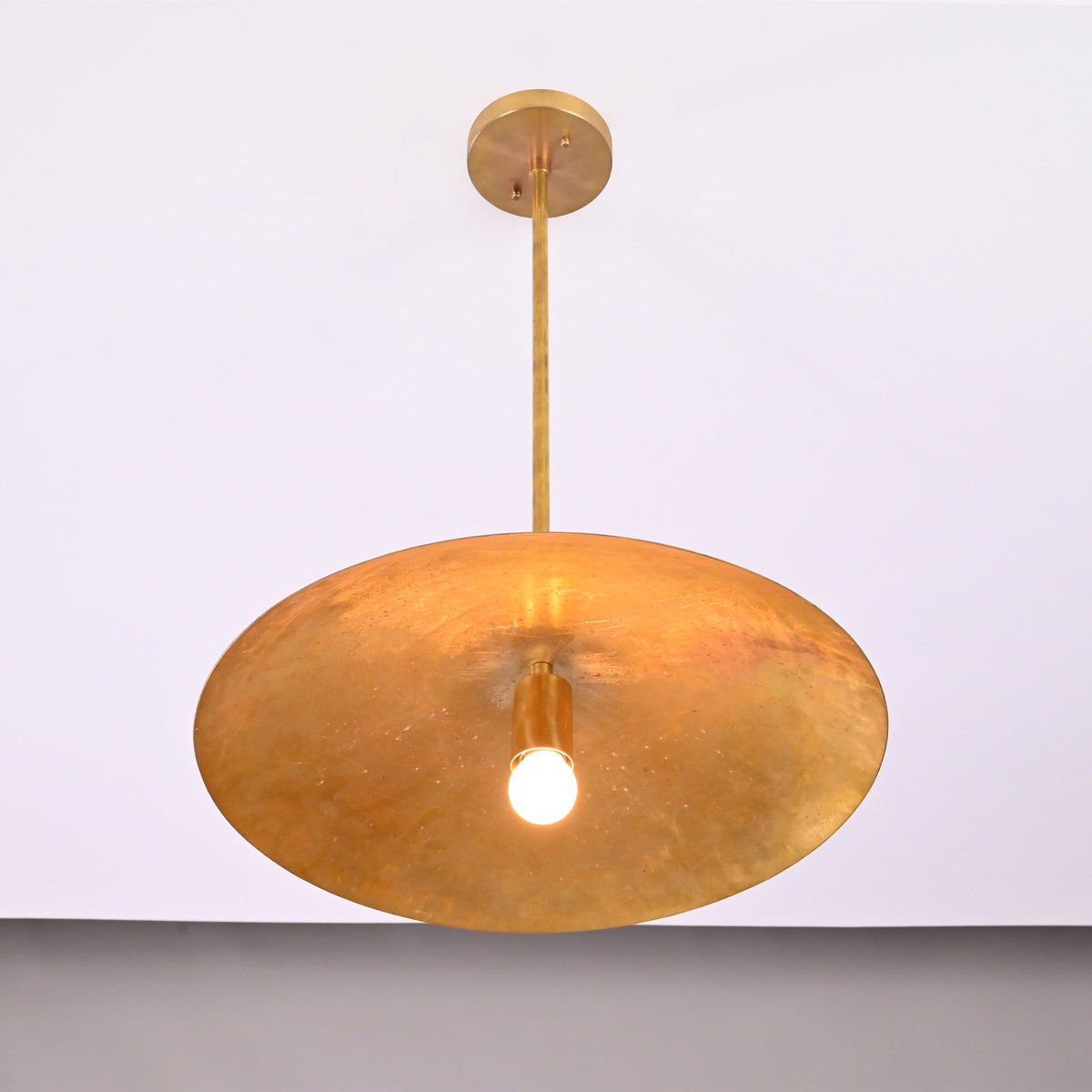 Underside view of Aurelia Petite Saucer Pendant Light showing the wide saucer shade and exposed glowing bulb.