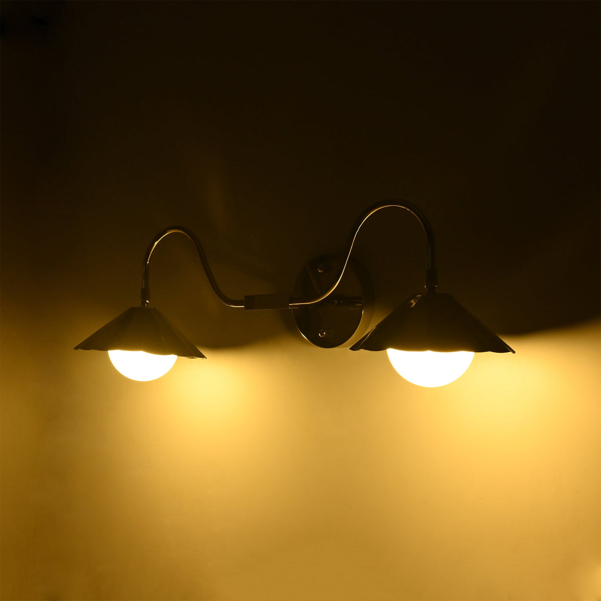 Perspective view of the Aurora modern polished nickel double wall sconce with illuminated frosted globe diffusers creating soft, even ambient lighting.