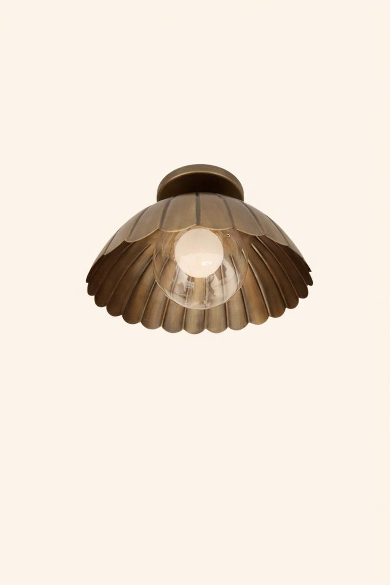 Underside view of brass scalloped dome ceiling light showing petal-edge bowl shade and central clear globe bulb.