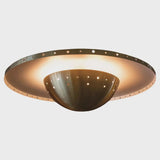 Brushed brass disc flushmount ceiling light with warm indirect glow and perforated bowl reflector.