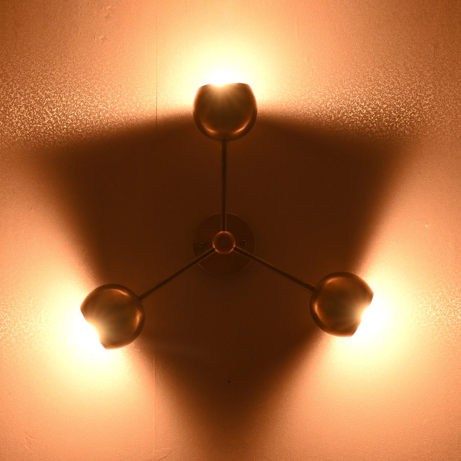 Modern brass flush mount ceiling light with three spherical shades in brushed brass finish, photographed against a light background.