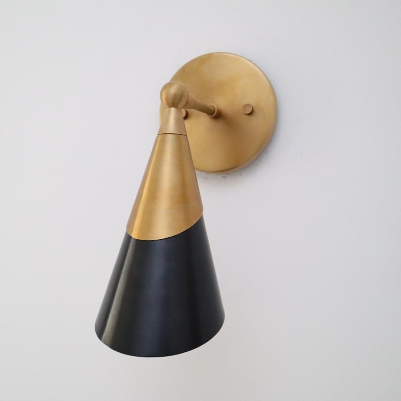 Brass and black cone wall light shown from a front-left angle with brushed brass arm and round mount.