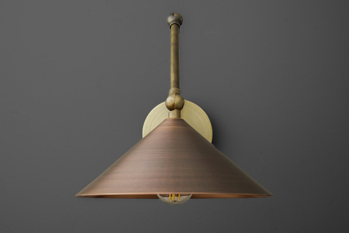 Front view of handmade brass wall sconce with cone shade, adjustable arm joints, warm brass finish, E26 bulb visible.