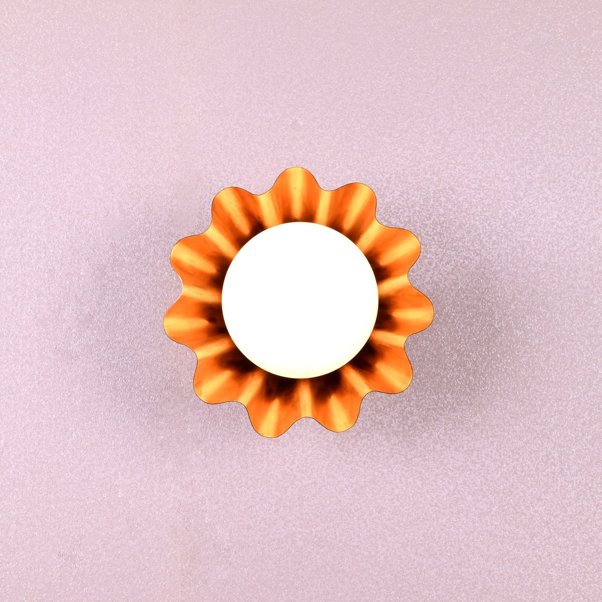 Handmade brass flower-shaped wall light with round bulb, viewed from the front, designed by Brass Leaf Studio.