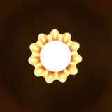 Brass flower-shaped wall light glowing in the dark, casting soft ambient illumination with petal shadow effect.