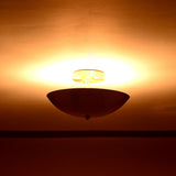 Elegant brushed brass ceiling light glowing warmly in softly lit interior setting