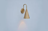 Elegant brushed brass cone wall lamp mounted on wall, showing refined silhouette and smooth finish.