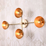 Capri Disc Linear Wall Light mounted on a bright patterned wall with four exposed bulbs and round shades.