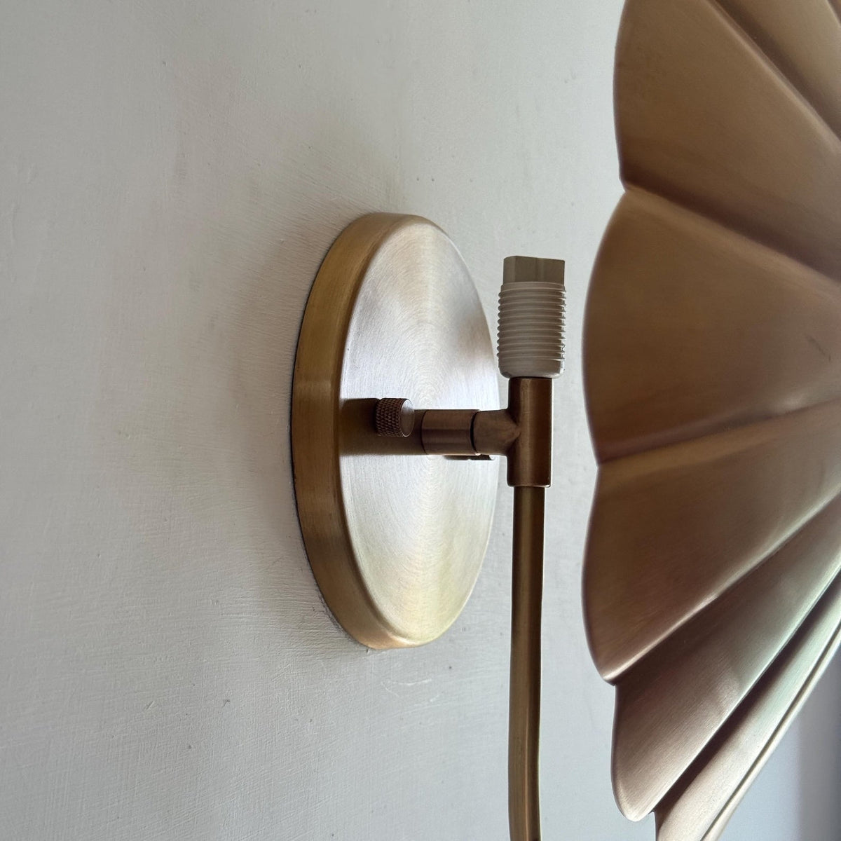 Close-up of round brass wall canopy and E26 socket holder with adjustable joint in brushed brass finish.