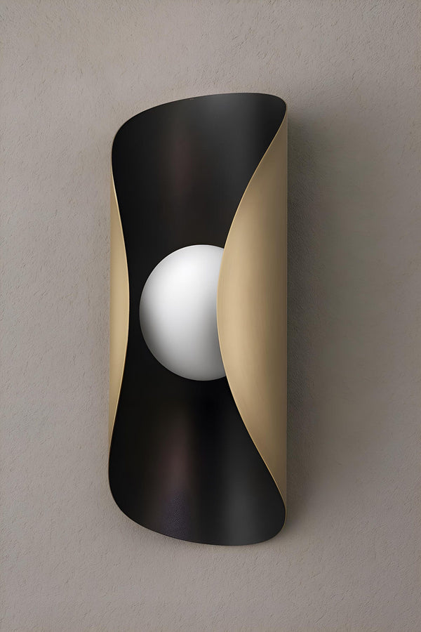Curved brass wall sconce with blackened exterior and brushed brass interior featuring a central frosted globe for soft ambient lighting