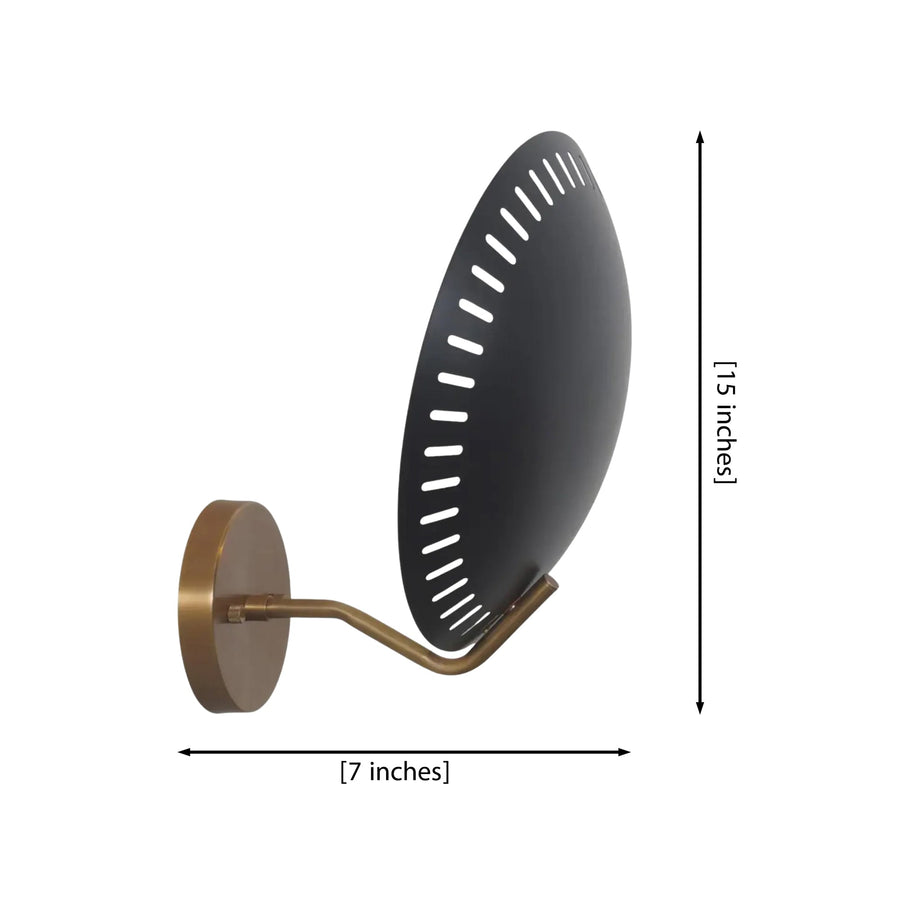 Eclipse perforated disc wall sconce illuminated in a modern living room beside an armchair with warm ambient lighting.