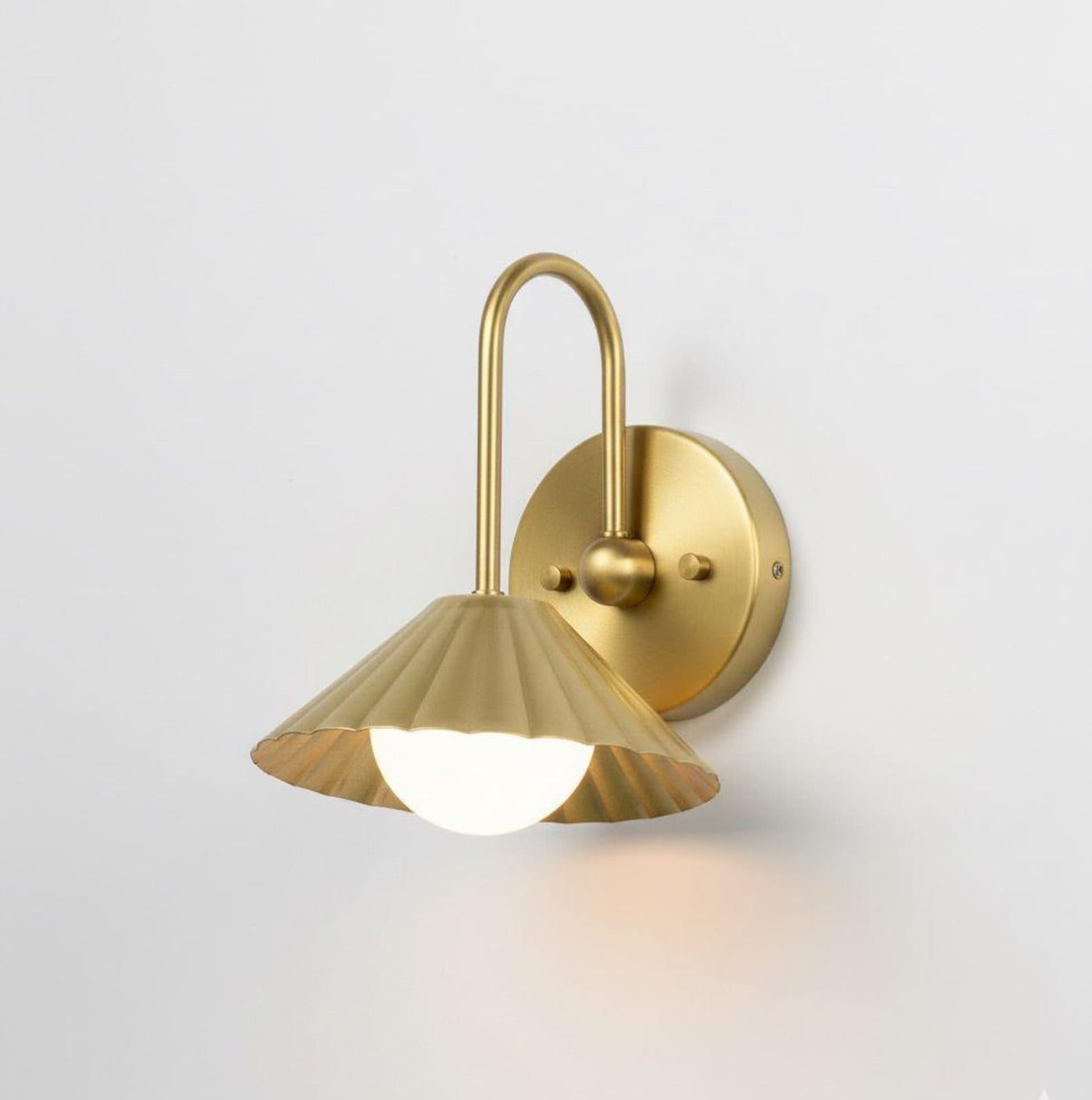 Side angle view of modern solid brass wall sconce with fluted shade and minimalist curved arm design