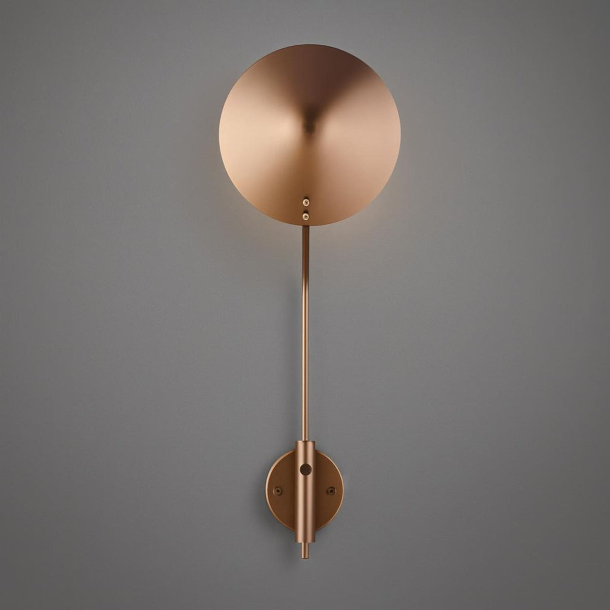 Front view of minimalist brass disc wall sconce with long stem and round backplate in brushed brass finish.