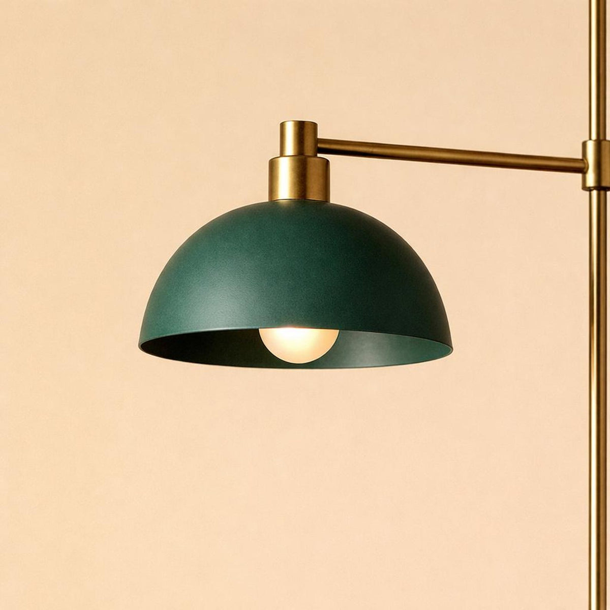 Close-up of a green metal dome pendant shade with brass detailing, casting a warm downward glow.