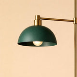 Close-up of a green metal dome pendant shade with brass detailing, casting a warm downward glow.
