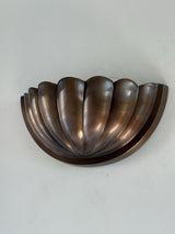 Handmade fluted scallop half-bowl wall sconce in aged brass/bronze finish, photographed mounted against a light wall.