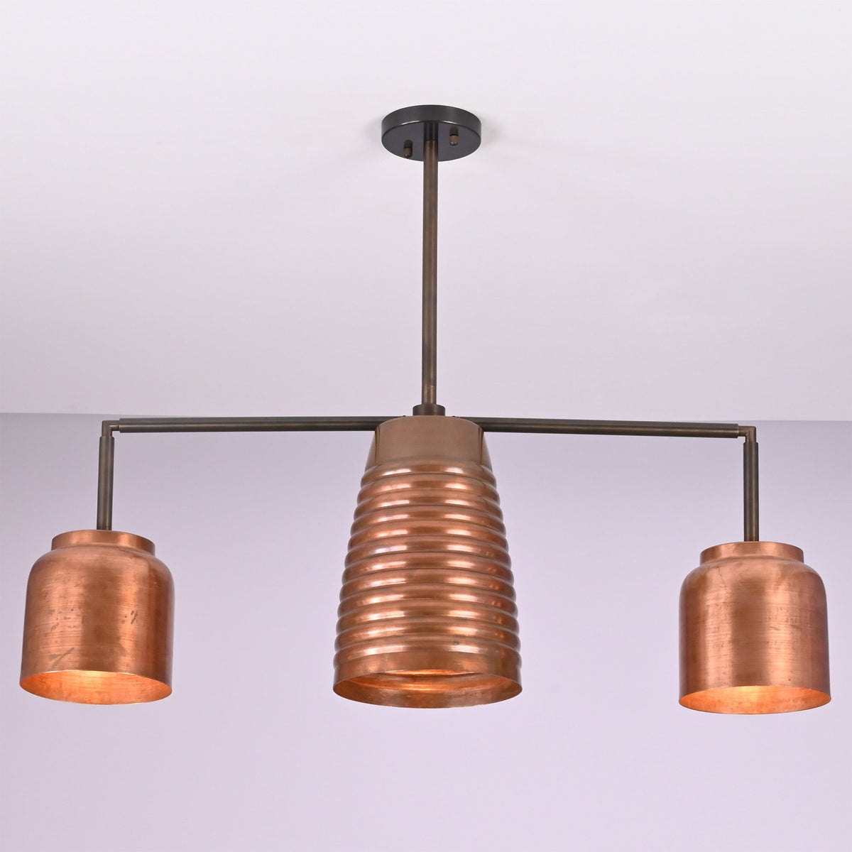 Angled view of the Hudson Modern Linear Copper Chandelier highlighting the ribbed center shade and balanced three-light design.