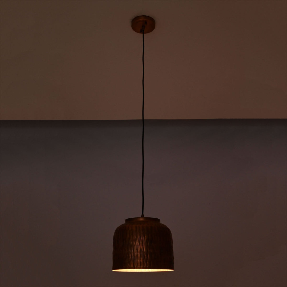 Hudson hammered copper dome pendant light at night emitting warm focused downward illumination