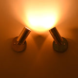 Antique brass adjustable cylinder wall sconce casting a focused warm directional beam, perfect for accent lighting and artwork illumination.