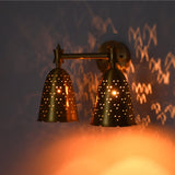 Angled illuminated double bell wall sconce creating decorative dotted light patterns and warm ambient glow.