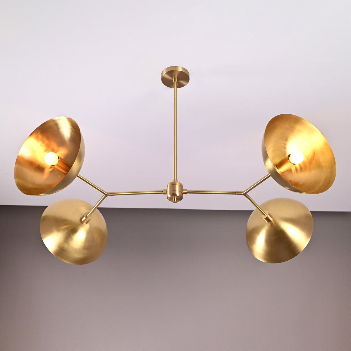 Madrid Orbital Chandelier glowing warmly on ceiling, creating dramatic shadows from angled disc shades.