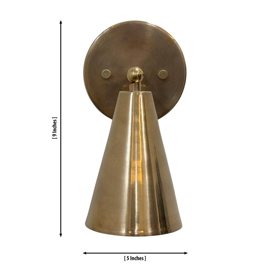 Milan adjustable brass cone wall sconce installed beside a bed in a modern bedroom, providing warm ambient lighting for Scandinavian and contemporary interiors.