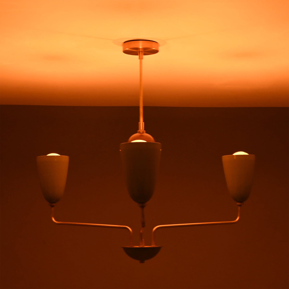 Milan Cone Arm Chandelier glowing warmly in low light with three upward-facing cone shades.