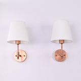Angled front view of the Milan copper antique brass wall sconce with a white tapered fabric shade, showcasing its elegant handcrafted design and compact wall-mounted profile.