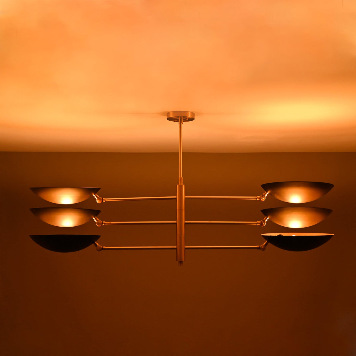 Milan Disc Linear Chandelier installed on ceiling with six black disc shades and warm upward glow.