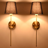 Milan navy shade wall sconces glowing warmly with tall rod frames and soft wall illumination.