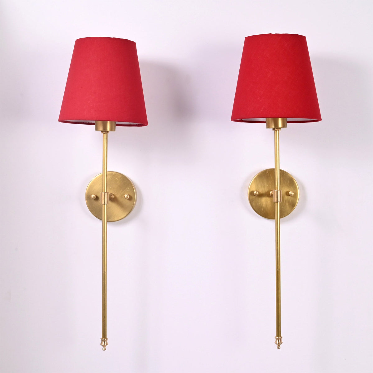 Pair of Milan red shade rod wall sconces with round wall plates and elegant long stem design.