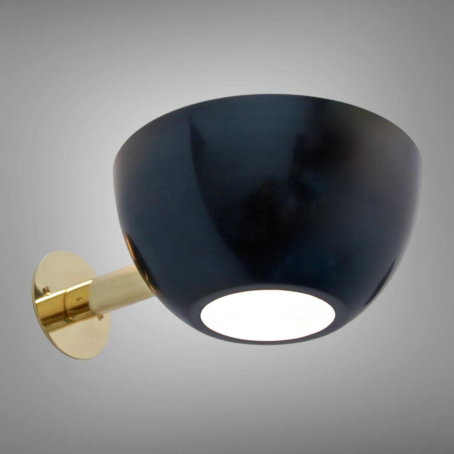 Modern bowl wall sconce with glossy black metal shade and polished brass backplate and arm on a gray background.
