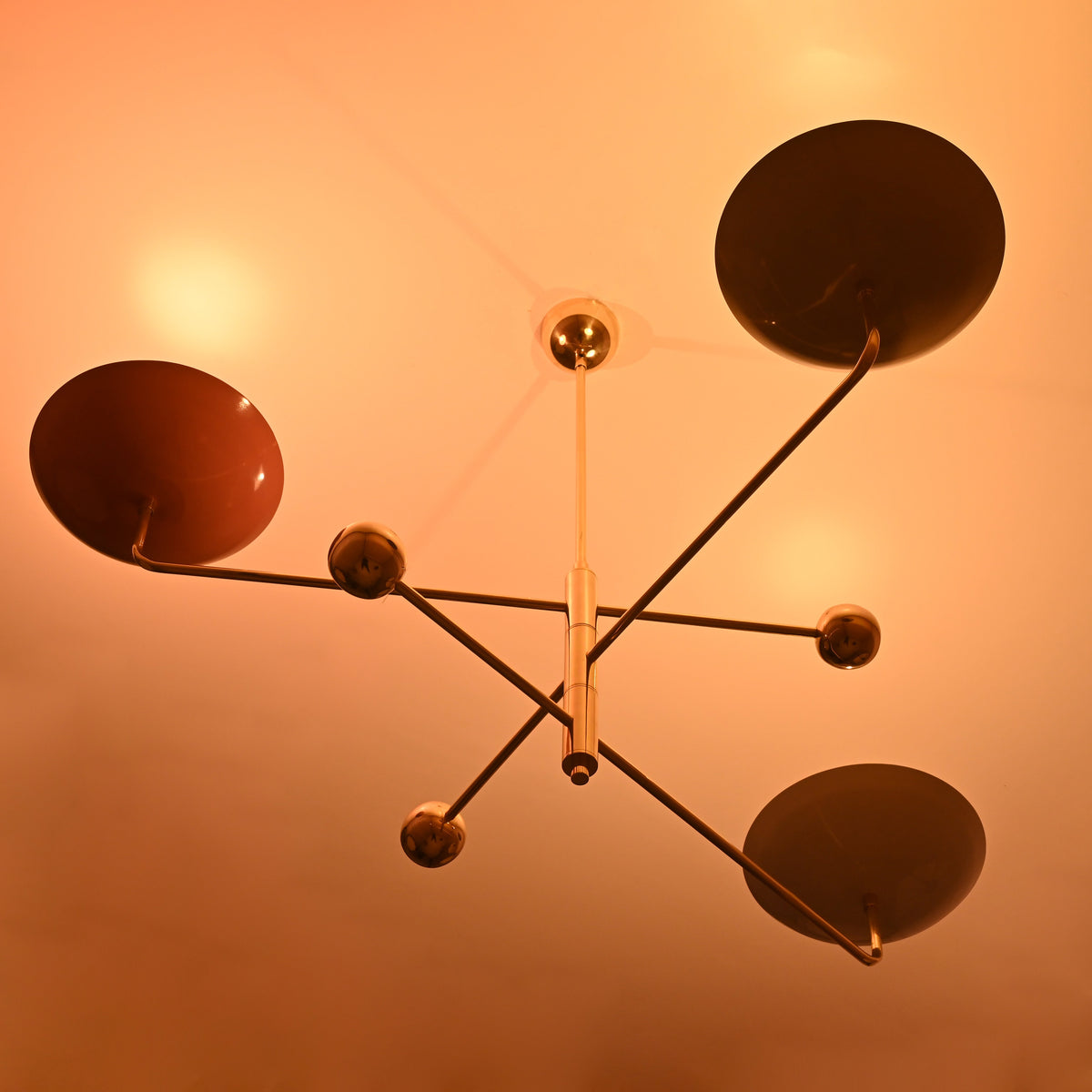 Brass chandelier with colorful shades casting soft golden glow, elegant modern design for ambient interior lighting.