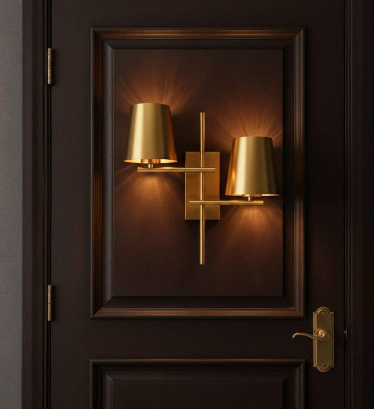 Lit brass double shade wall sconce installed on a dark wood paneled door, casting a warm decorative glow.