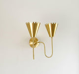 Angled perspective of brushed brass double cone wall light with decorative crown rim shades and curved tubular arms