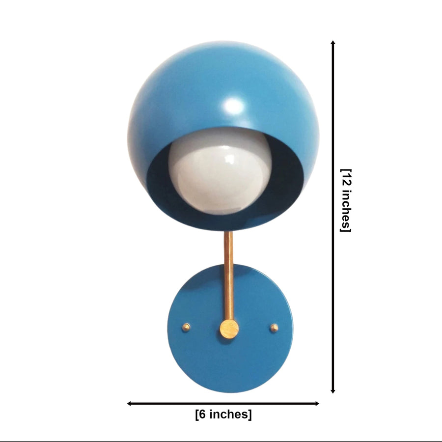 Blue Oslo dome wall sconce illuminated in a cozy modern reading corner with warm ambient lighting.
