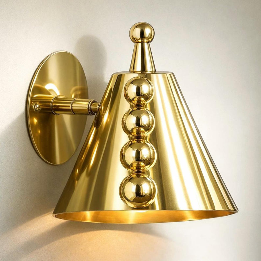 Front view of polished brass cone wall sconce with ball accents and round backplate mounted on a textured wall.