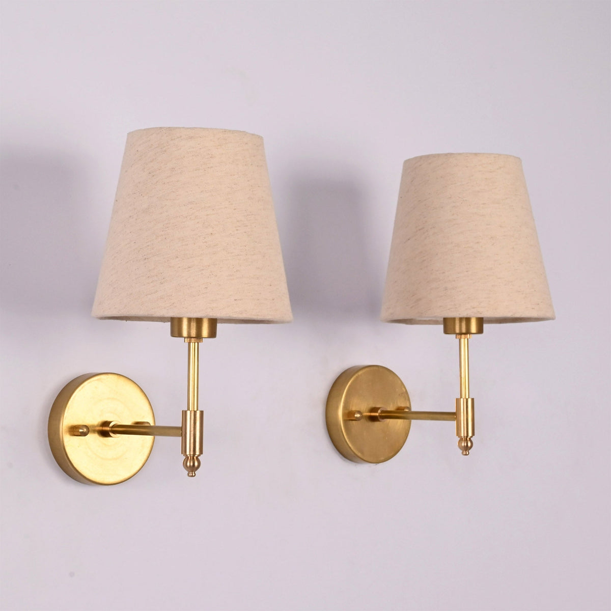 Rear angled view of the Milan brushed brass wall sconce featuring a natural linen fabric shade and round wall backplate.