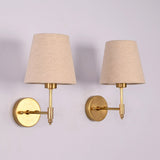 Rear angled view of the Milan brushed brass wall sconce featuring a natural linen fabric shade and round wall backplate.