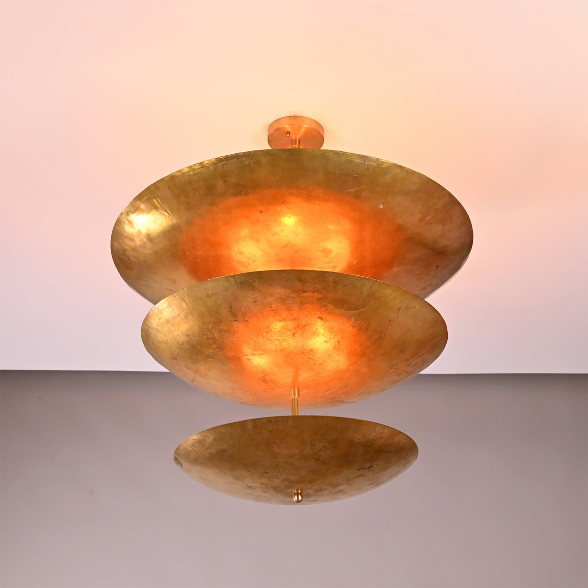 Siena Three Tier Disc Chandelier installed on ceiling, showing sculptural stacked disc form and soft reflected lighting.