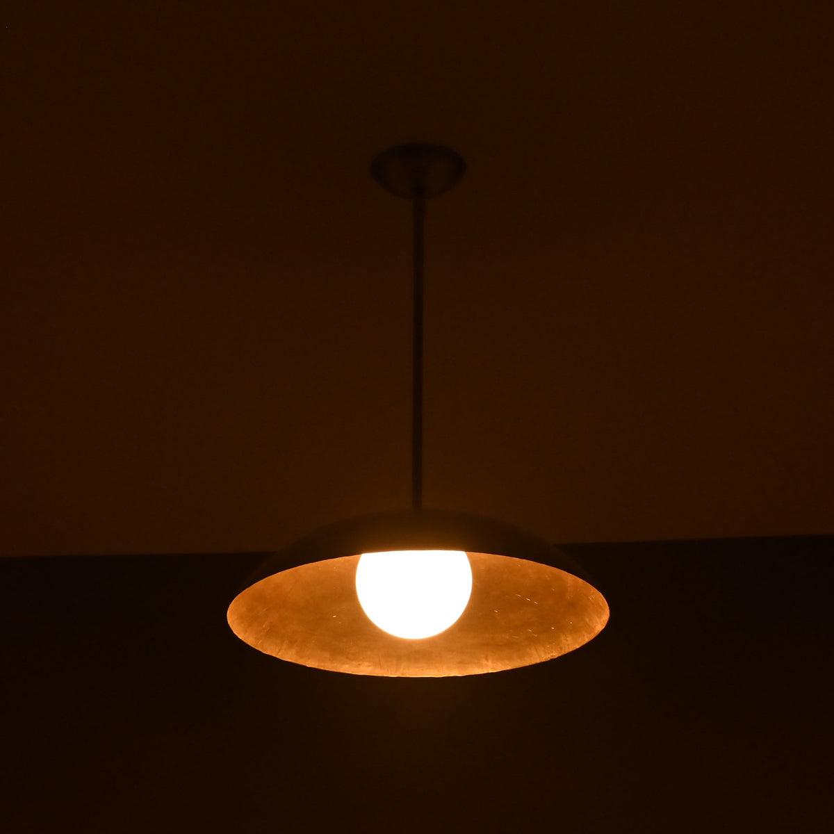 Full view of glowing single dome brass pendant lamp, modern handmade ceiling lighting design