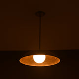 Wide view of lit brass pendant light casting ambient golden light, handmade by Brass Leaf Studio